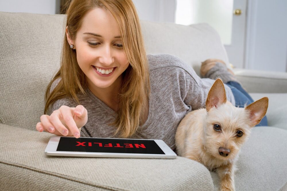 犬とタブレットでNetflixを視聴する女性