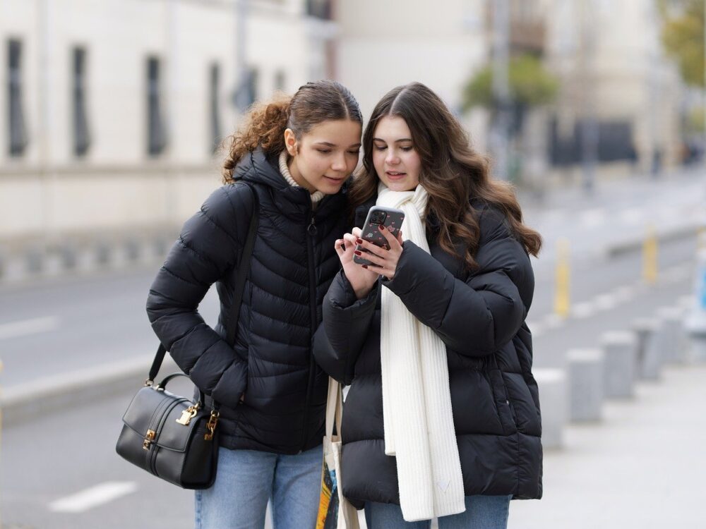 スマホを友人に見せる女性