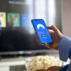 テレビの前でVPNの画面が表示されたスマホを持つ人物。